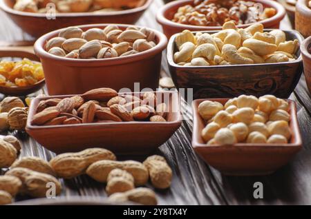 Verschiedene Nüsse und Samen in Tonschüsseln auf Holzküche Tabelle Stockfoto