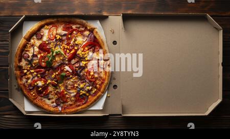 Paprika-Pizza mit Paprika, Zuckermais und Rucola in offener Schachtel auf dunklem Holztisch flach liegend mit Kopierraum Stockfoto