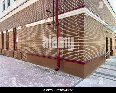 Gebäude nach Renovierungsarbeiten. Ecke des Fabrikgebäudes mit Metallabflussrohr. Stockfoto