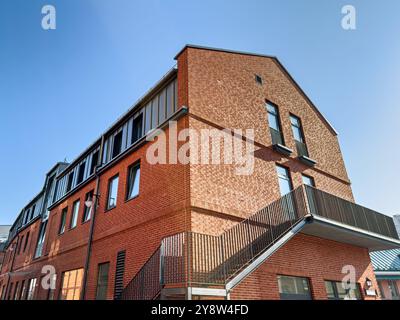 Renoviertes altes industrielles Backsteingebäude mit einer Feuerleiter vor blauem Himmel. Stockfoto