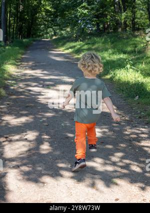 Kleiner Junge, der auf dem Waldweg springt Stockfoto