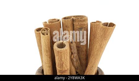 Ein detailliertes Nahbild von Zimtstäbchen in einer Holzschale vor weißem Hintergrund. Perfekt für Themen wie Gewürze, Kochen und natürliches i Stockfoto