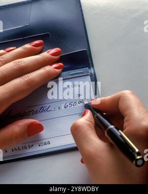 1991 HISTORISCHE HÄNDE EINER FRAU, DIE PAPIER SCHREIBT BANKSCHECK MIT TINTENFÜLLFEDERHALTER Stockfoto
