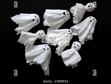 Eine Gruppe von Geistern auf schwarzem Hintergrund. Handgefertigt aus Servietten. Verschiedene Gesichtsausdrücke werden mit einem Marker gezeichnet. Diagonal in einem Dreieck platziert. Köpfe t Stockfoto