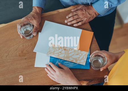 Zwei Leute halten Gläser Wasser, lesen Dokumente auf einem Holztisch, besprechen Details. Hochwertige Fotos Stockfoto
