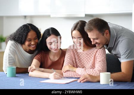 Vier glückliche Mitbewohner unterzeichnen einen Vertrag in der Küche zu Hause Stockfoto
