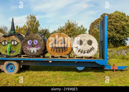 Gemalte Gesichter auf Strohballen in Holmeswood, Lancashire Oktober 2024 Blauer Himmel und ein sonniger Nachmittag, während die Vorbereitungen für die halbtägige Besucherattraktion für Kürbis an diesem Wochenende beginnen. Emoji-Kunst mit verzierten bemalten Strohballen am Eingang der Farm kündigen die Halloween-Veranstaltung an Stockfoto