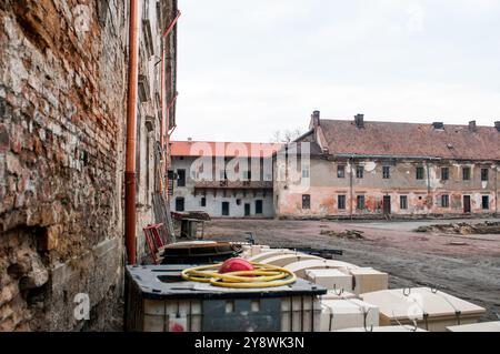 Verlassener Industriekomplex, umgeben von bröckelnden Ziegelmauern und bewachsenem Gelände. Stockfoto