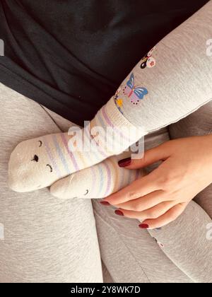 Kuschelige, bunte Babysocken in Hygge-Pastellfarben auf neutralem beigefarbenem Hintergrund. Ästhetische minimalistische Baby-Fashion-Collage. Glückliches Mutterschaftskonzept. Hoch q Stockfoto