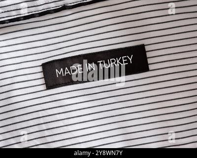 Nahaufnahme eines Labels Made in Turkey, das in ein weiß gestreiftes Hemd genäht ist und die türkische Textilherstellung unterstreicht Stockfoto