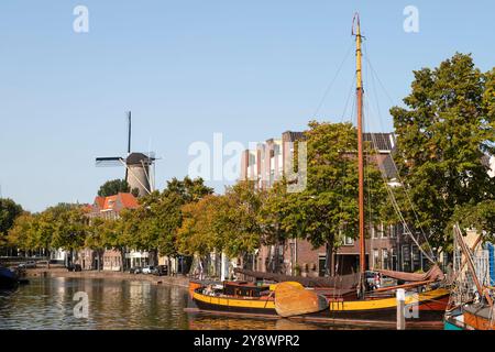Historischer alter Hafen mit einem alten Segelschiff und einer Windmühle im Hintergrund im Zentrum von Schiedam. Stockfoto