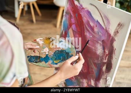 Eine junge Frau mit kurzen Haaren auf einer Leinwand, die ihr künstlerisches Hobby in einer gemütlichen Umgebung annimmt. Stockfoto