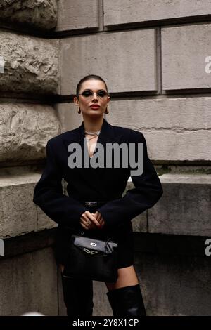 Polina Erofeeva mit komplett schwarzem Outfit kombiniert mit einem übergroßen Blazer, Minirock, Stiefeln und einem birkin auf der Hermès Show in der Pariser Fashion Week SS25 Stockfoto