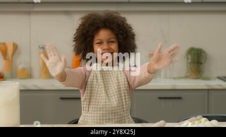 Afroamerikaner glücklich lächelnd positiv fröhliche ethnische kleine Mädchen Familie adoptierte Kind Kind Tochter allein auf Schürze winkte hallo Lächeln Begrüßung Stockfoto