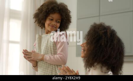 Glückliche afroamerikanische Familienfrau weibliche Mutter Mutter Mutter zusammen macht Spaß in der Küche kleines Kind Kind Mädchen Tochter tanzt Musik tanzen in Stockfoto