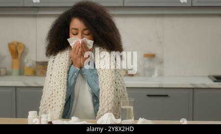 Kranke allergische afroamerikanische Frau Niesen in Papiergewebe Blasen Nase zu Hause Küche kranke Mädchen Grippe ethnische weibliche Dame Allergie Symptome ungesund Stockfoto