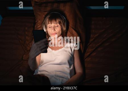 Abhängigkeit von der mobilen Nutzung. Süchtig nach Social Media Frau, die nachts mit Handy in ihrem Bett einschlief. Kopierbereich Stockfoto
