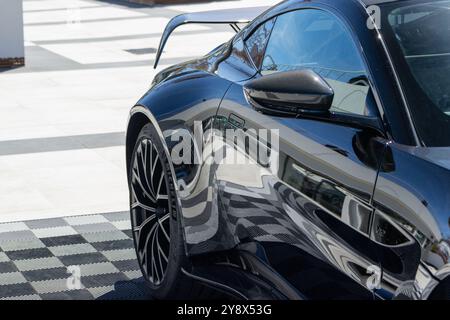 Aston martin Vantage Coupé mit tiefem, sauberem Glanz ist geparkt und spiegelt die Umgebung in seiner polierten schwarzen Farbe wider Stockfoto