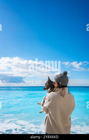 Frau, die einen Hund am Strand von Porto Katsiki hält und lächelt Stockfoto