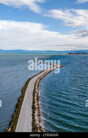 Drohnenansicht der Straße mit Kurven zwischen zwei Seen in Koronisia, Griechenland Stockfoto