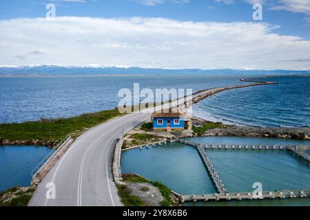 Drohnenblick auf blaues Haus auf der Straße mit Kurven zwischen zwei Seen, Griechenland Stockfoto