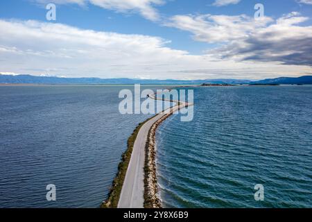 Drohnenansicht der Straße mit Kurven zwischen zwei Seen in Koronisia, Griechenland Stockfoto