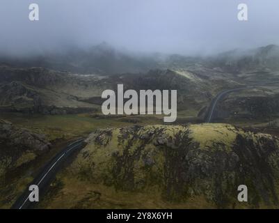 Nebelige Landschaft mit gewundenen Straßen durch Berge Stockfoto