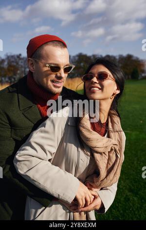 Ein nettes Paar umarmt sich herzlich und teilt ein Lächeln an einem frischen Herbsttag im Park. Stockfoto