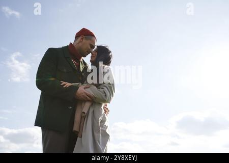 Ein liebevolles Paar teilt einen zärtlichen Moment in warmer Kleidung vor einer wunderschönen Herbstkulisse. Stockfoto