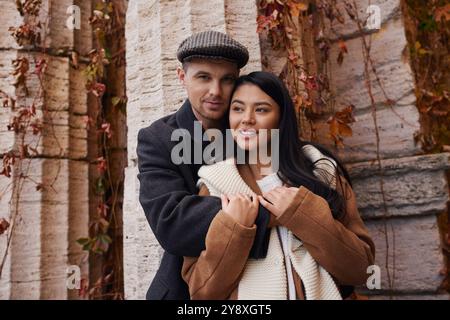 Ein Paar umarmt sich herzlich und genießt einen ruhigen Herbsttag inmitten farbenfroher Blätter. Stockfoto