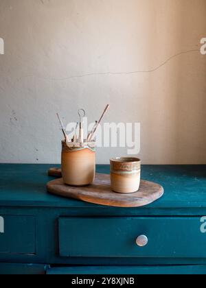 Schöne handwerkliche Töpferkomposition, Tassen, Schüsseln und Werkzeuge auf einem blauen Schrank, handgefertigt in frankreich, rustikaler Stil Stockfoto