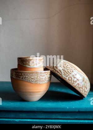 Schöne handwerkliche Töpferkomposition, Tassen, Schüsseln und Werkzeuge auf einem blauen Schrank, handgefertigt in frankreich, rustikaler Stil Stockfoto