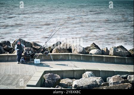 Angler fischen vor der Ufermauer in Rossall. Fleetwood, Großbritannien Stockfoto