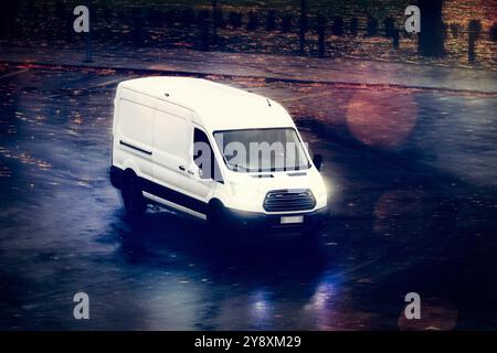 Weißer Lieferwagen transportiert Waren an einem dunklen Herbstabend mit erhöhter Aussicht. Stockfoto