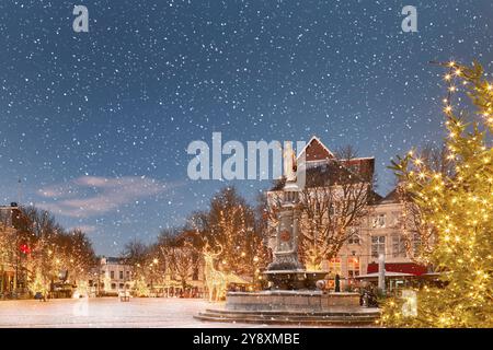 Winterblick mit Schneefall auf den zentralen historischen Platz mit Bars und Restaurants im alten Stadtzentrum von Deventer, Niederlande Stockfoto