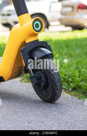 Ein leuchtend gelber Roller parkt ordentlich am Straßenrand und wartet darauf, dass der Besitzer zurückkehrt und sich im Sonnenlicht sonnt Stockfoto