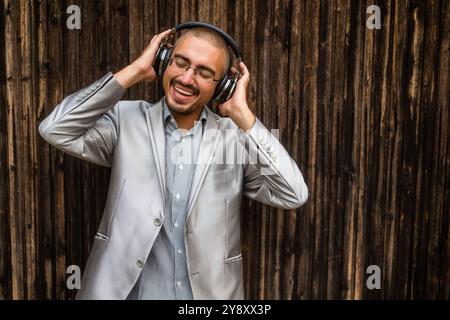 Porträt eines glücklichen Geschäftsmannes mit Kopfhörern. Hölzerner Hintergrund. Stockfoto
