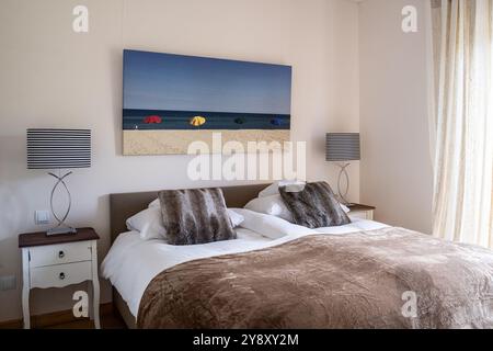 Strandszene über Doppelbett mit Pelzüberwürfen in spanischer Villa auf Mallorca. Stockfoto