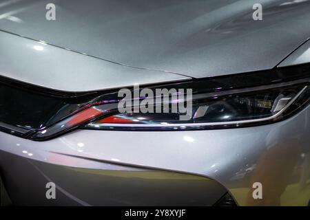 Das Bild zeigt eine detaillierte Nahaufnahme des Scheinwerfers eines schlanken, glänzenden Autos und zeigt sein Design und seine Beleuchtungsmerkmale Stockfoto