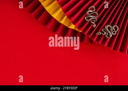 Chinesisches asien Neujahr goldener roter Hintergrund. Neue Grußkarte für das Jahr der Schlange 2025 mit Sternzeichen. Roter flacher Hintergrund mit Weihnachtsfans, Wunschumschläge, sn Stockfoto