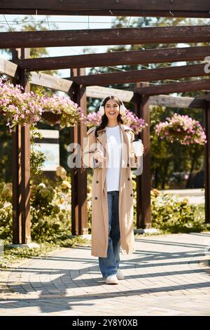 Eine junge Frau entspannt sich in einem sonnigen Park, stilvoll gekleidet und schlürft ein warmes Getränk. Stockfoto