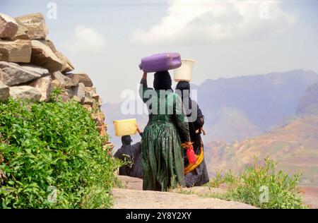 Frauen in traditioneller Jemen-Kleidung auf dem Heimweg mit Wasser aus einem Brunnen in der Nähe der jemenitischen Stadt Marib Stockfoto