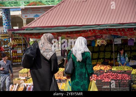 Taschkent,Usbekistan;September,16,2024: Zwei muslimische Frauen in traditionellen Hijabs gehen Seite an Seite durch den lebhaften Obstmarkt in Taschkent Stockfoto