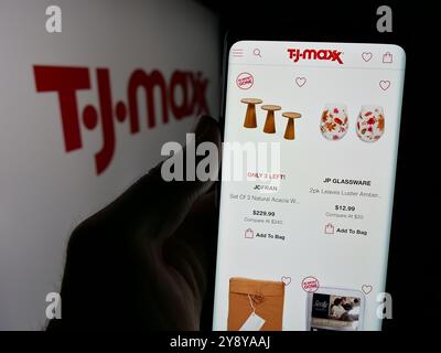 Person, die ein Mobiltelefon hält, mit Webseite der US-Rabattfirma TJ Maxx auf dem Bildschirm mit Logo. Konzentrieren Sie sich auf die Mitte des Telefondisplays. Stockfoto