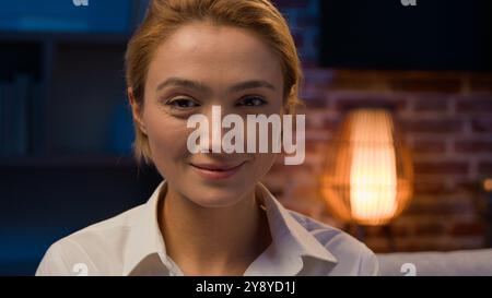 Lächelnde kaukasische Erwachsene Frau mittleren Alters, die in die Kamera blickt Happy Lächeln in der Nacht zu Hause. Sorglose Millennial-Freizeit-Profi-Frau weiblich Stockfoto