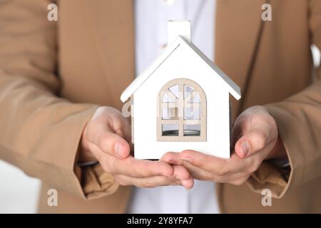 Sachversicherung. Immobilienmakler mit Hausfigur auf hellem Hintergrund, Nahaufnahme Stockfoto