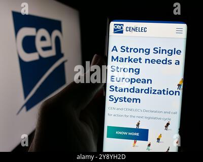 Person, die ein Mobiltelefon hält, auf der Webseite des Europäischen Komitees für Normung (CEN) mit Logo auf dem Bildschirm angezeigt wird. Konzentrieren Sie sich auf die Mitte des Telefondisplays. Stockfoto