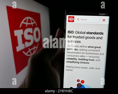 Person, die das Telefon hält, mit der Webseite der Internationalen Organisation für Normung (ISO) auf dem Bildschirm mit Logo. Konzentrieren Sie sich auf die Mitte des Telefondisplays. Stockfoto