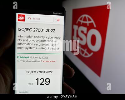 Person, die das Telefon mit der Website der Internationalen Organisation für Normung (ISO) auf dem Bildschirm mit Logo hält. Konzentrieren Sie sich auf die Mitte des Telefondisplays. Stockfoto