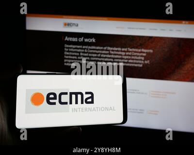 Person mit Smartphone und Logo der Normungsorganisation Ecma International auf dem Bildschirm vor der Website. Schwerpunkt auf dem Display des Telefons. Stockfoto